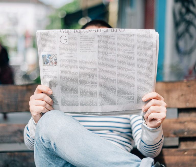 Strasser Design Ingenium – Grafikdesign, Texte, Konzepte Mann mit Zeitung vor dem Gesicht.