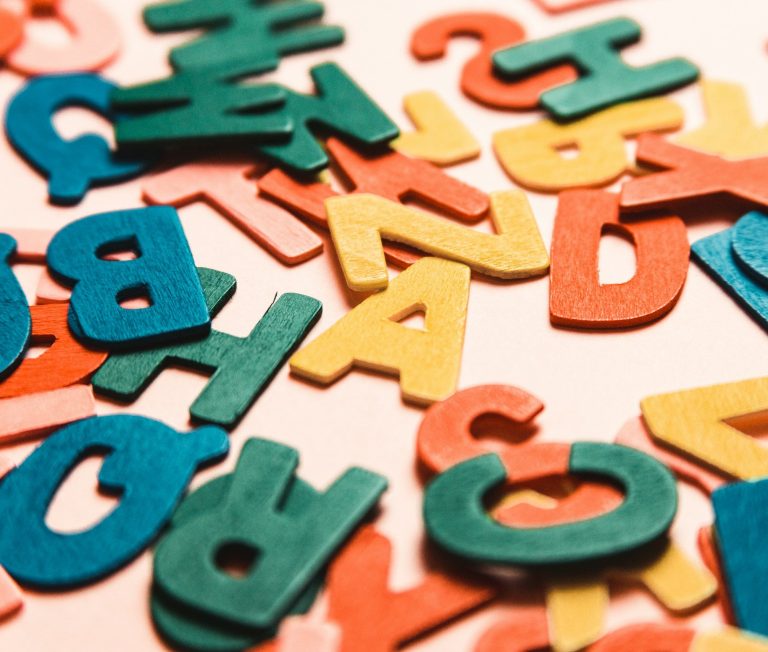 Strasser Design Ingenium – Grafikdesign, Texte, Konzepte Bunte Buchstaben liegen auf einem Tisch.
