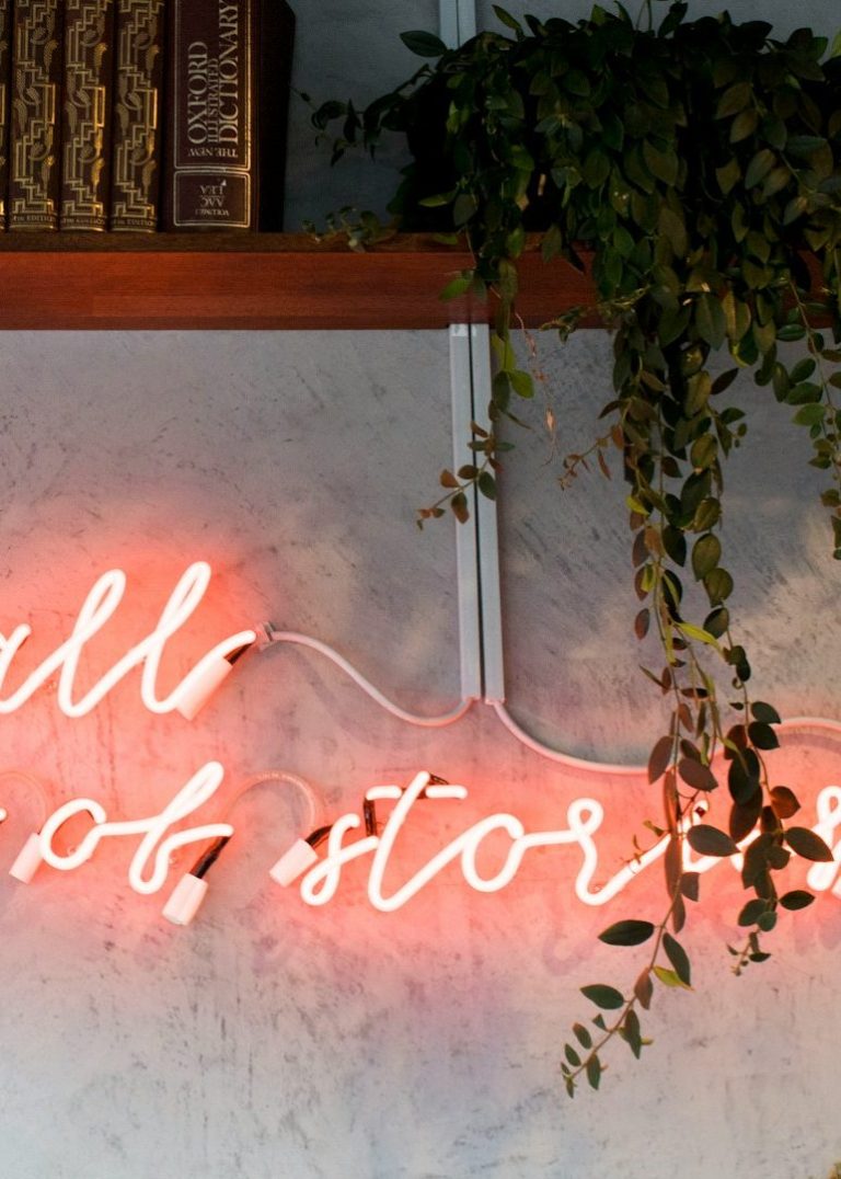 Strasser Design Ingenium – Grafikdesign, Texte, Konzepte Wand mit Regal und einer Neonschrift.