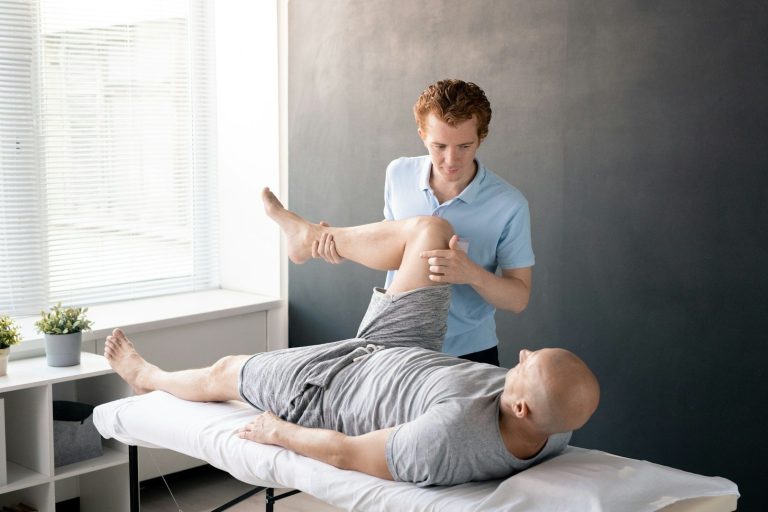 Strasser Design Ingenium – Grafikdesign, Texte, Konzepte Physiotherapeut behandelt älteren Mann auf einer Liege.