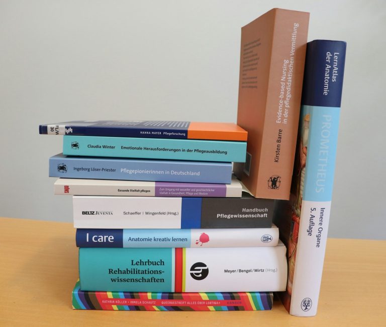 Strasser Design Ingenium – Grafikdesign, Texte, Konzepte Stapel unterschiedlicher Bücher.