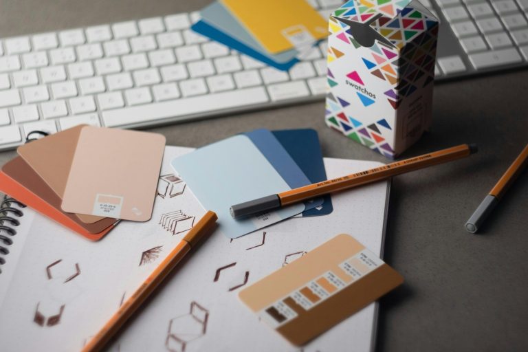 Strasser Design Ingenium – Grafikdesign, Texte, Konzepte Utensilien und Farbkarten auf einem Schreibtisch.